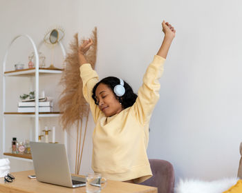 African-american female stretching after working on laptop. listening to music in earphones
