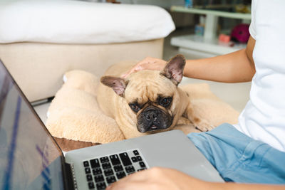 Midsection of woman using digital tablet while sitting on sofa at home