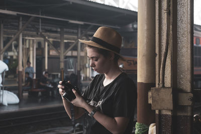 Young woman using mobile phone while standing at camera