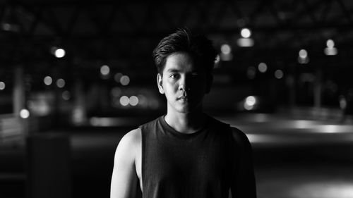 Portrait of young man standing against illuminated lights