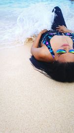 Waves splashing on woman lying down at beach