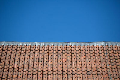 Low angle view of brick wall against blue sky