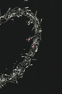 Low angle view of illuminated ferris wheel against black background