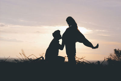 Silhouette couple standing on land against sky during sunset