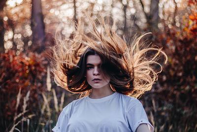 Portrait of young woman with tousled hair in forest