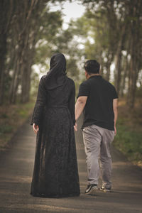 Rear view of couple walking against trees