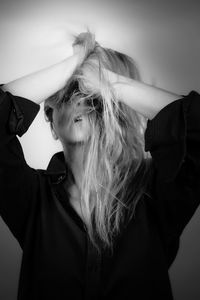 Portrait of young woman standing against wall