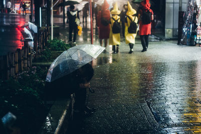 People walking on wet road during rainy season