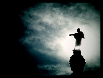 Low angle view of silhouette people against cloudy sky
