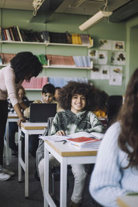 Smiling student with curly hair sitting at desk in classroom