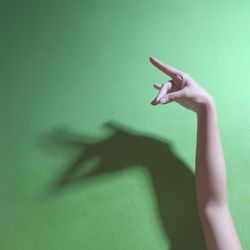 Close-up of hand gesture over green background