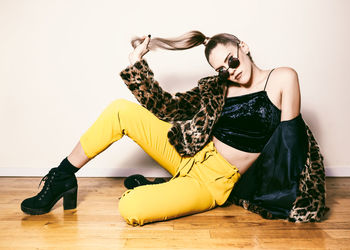 Young woman wearing sunglasses while sitting on floor