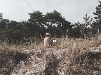 Shirtless man reading book on land