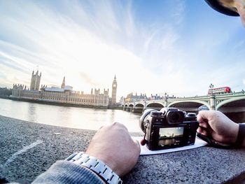 Cropped image of man photographing thames river and big ben through digital camera