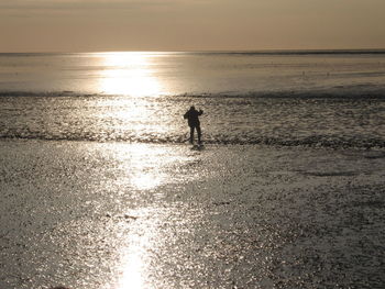 Silhouette man standing on beach against sky during sunset