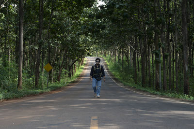 Rear view of woman walking on road amidst trees