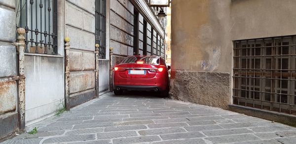 Red car on street amidst buildings in city