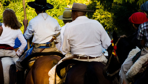 Rear view of people riding horses in forest