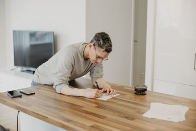 Woman writing on kitchen worktop