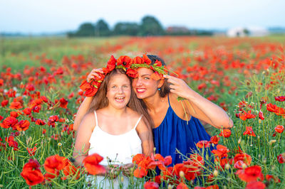 Beautiful young woman with child girl in poppy field, happy family having fun in nature, summer time