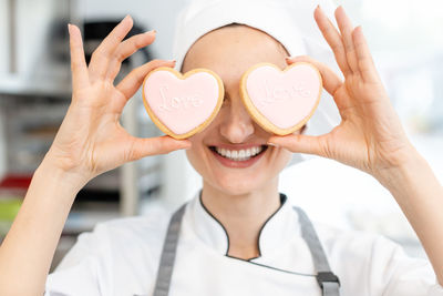 Woman holding heart shape cookies with text over eyes