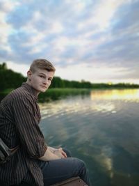 Portrait of young man sitting by lake