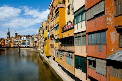 Buildings by canal against sky in city