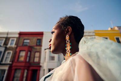 Portrait of woman looking away against colourful buildings