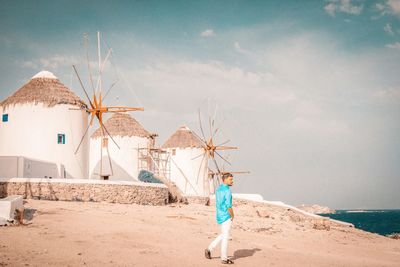 Full length of man walking at beach against sky and traditional windmills