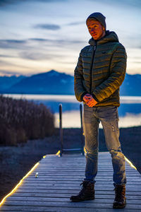 Man standing on pier by sea against sky