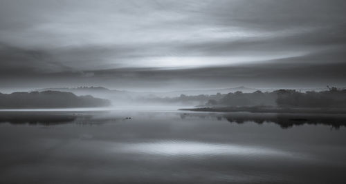 Scenic view of lake against sky during foggy weather