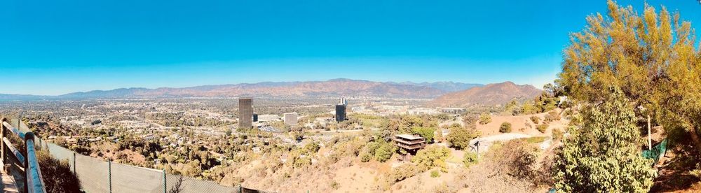 Panoramic view of people on landscape against blue sky