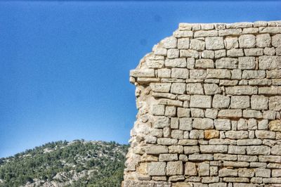 Low angle view of stone wall against blue sky