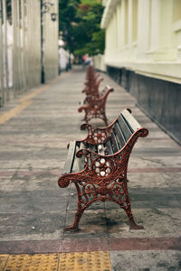 A row of classic wooden bench with iron black legs on a stone sidewalk city