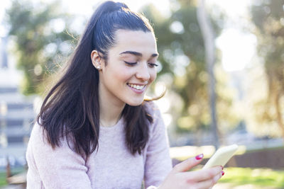 Smiling young woman using mobile phone