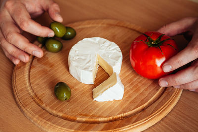 Cropped hands of person holding food on wooden cutting board