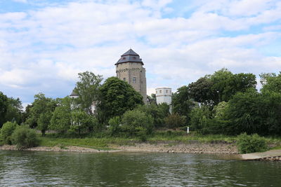 River by trees and buildings against sky