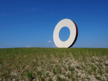 Information sign on field against clear blue sky