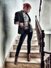 Full length portrait of young woman standing on staircase