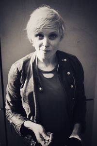 Portrait of young woman standing against wall