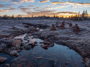 Rocks on shore during winter against sky