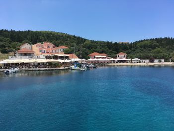 Houses by sea against clear blue sky