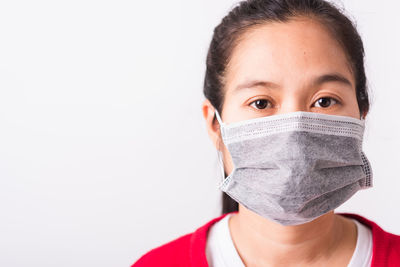 Portrait of woman wearing flu mask standing against white background