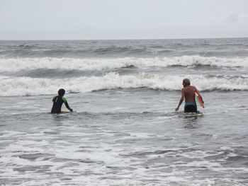 People surfing in sea against sky