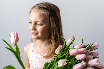 Portrait of smiling woman with pink tulips against white background