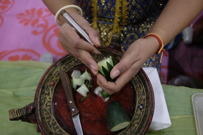 High angle view of woman carving vegetable at table