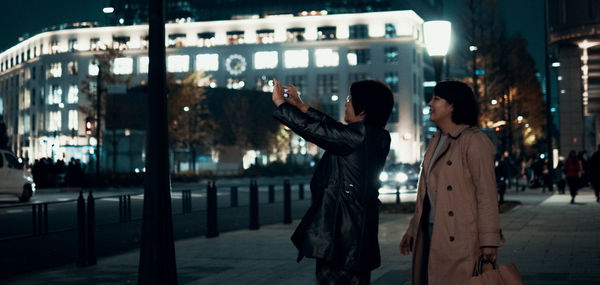 People standing on street in city at night