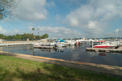 Sailboats moored at harbor against sky