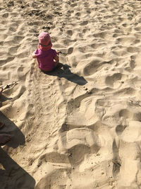 High angle view of girl sitting on sand at beach