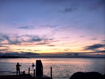 Silhouette man on beach against sky during sunset